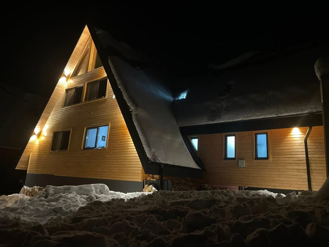 The cabin lit up at night, in the snow